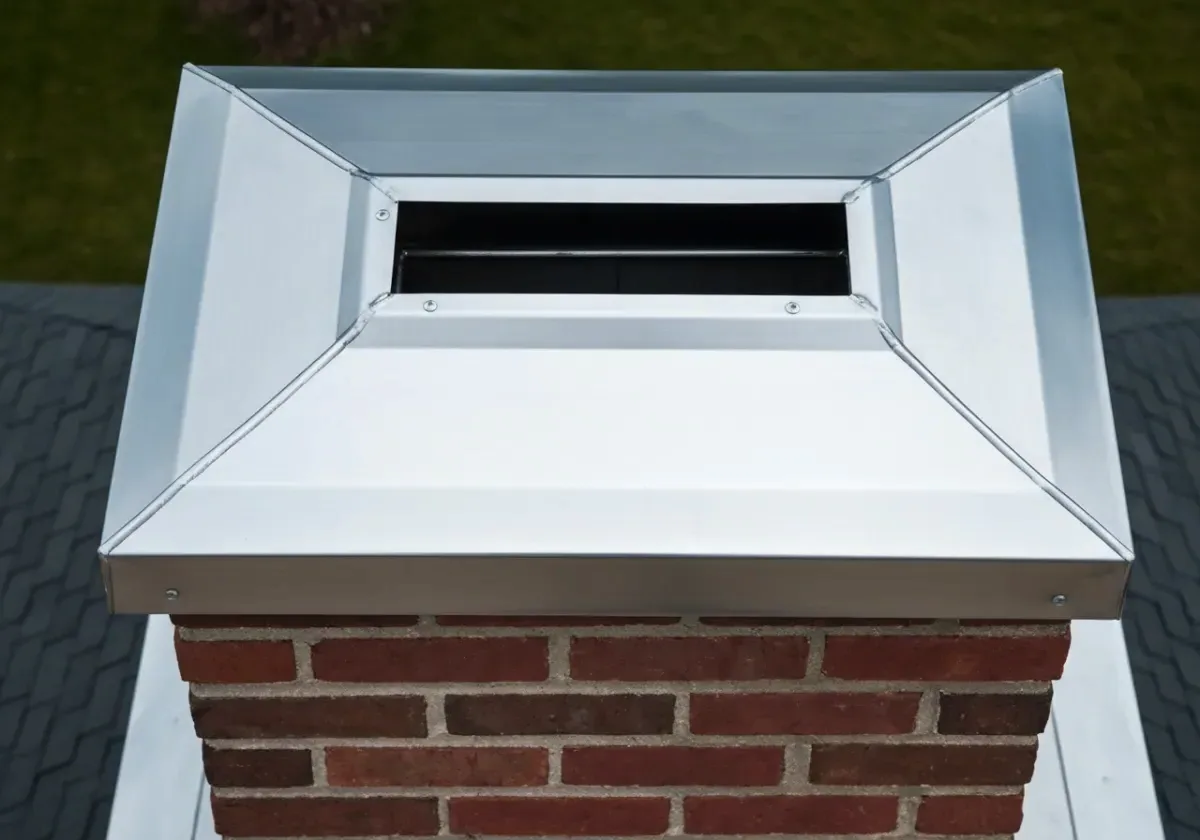 After — chimney cap installation: A bare, open flue topped with a stainless cap — rain and nesting birds shut out.